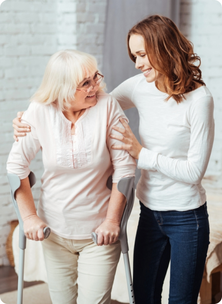 A woman assists an elderly woman with a walker.