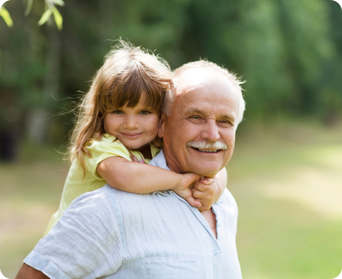 An older man and a little girl standing in the grass.