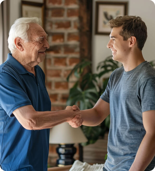 Two men shaking hands, one young and one old, in a professional setting.