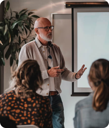 A man presenting to a group of people in a conference room.