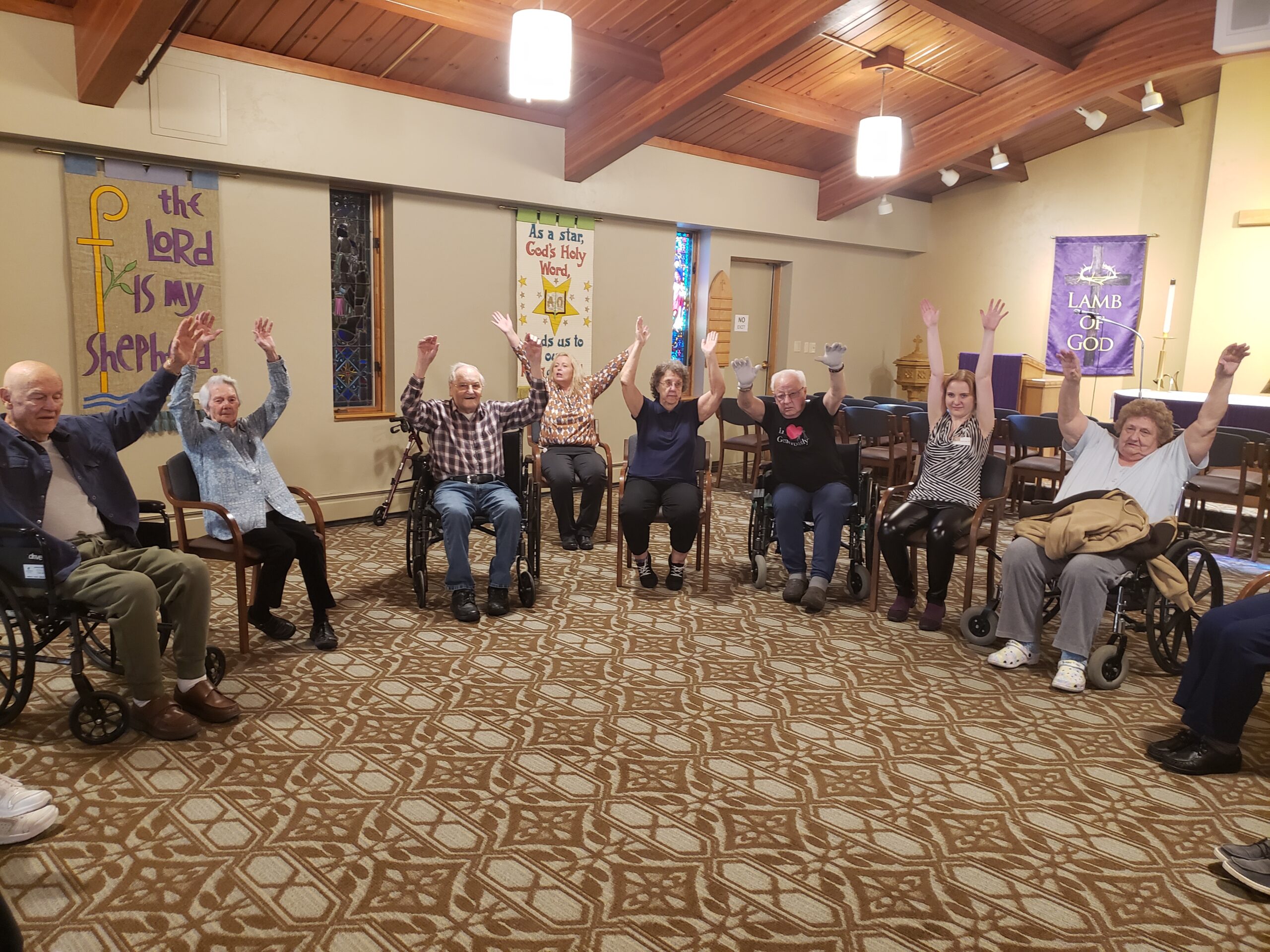 A group of elderly individuals in wheelchairs, joyfully raising their arms in a display of enthusiasm and camaraderie.