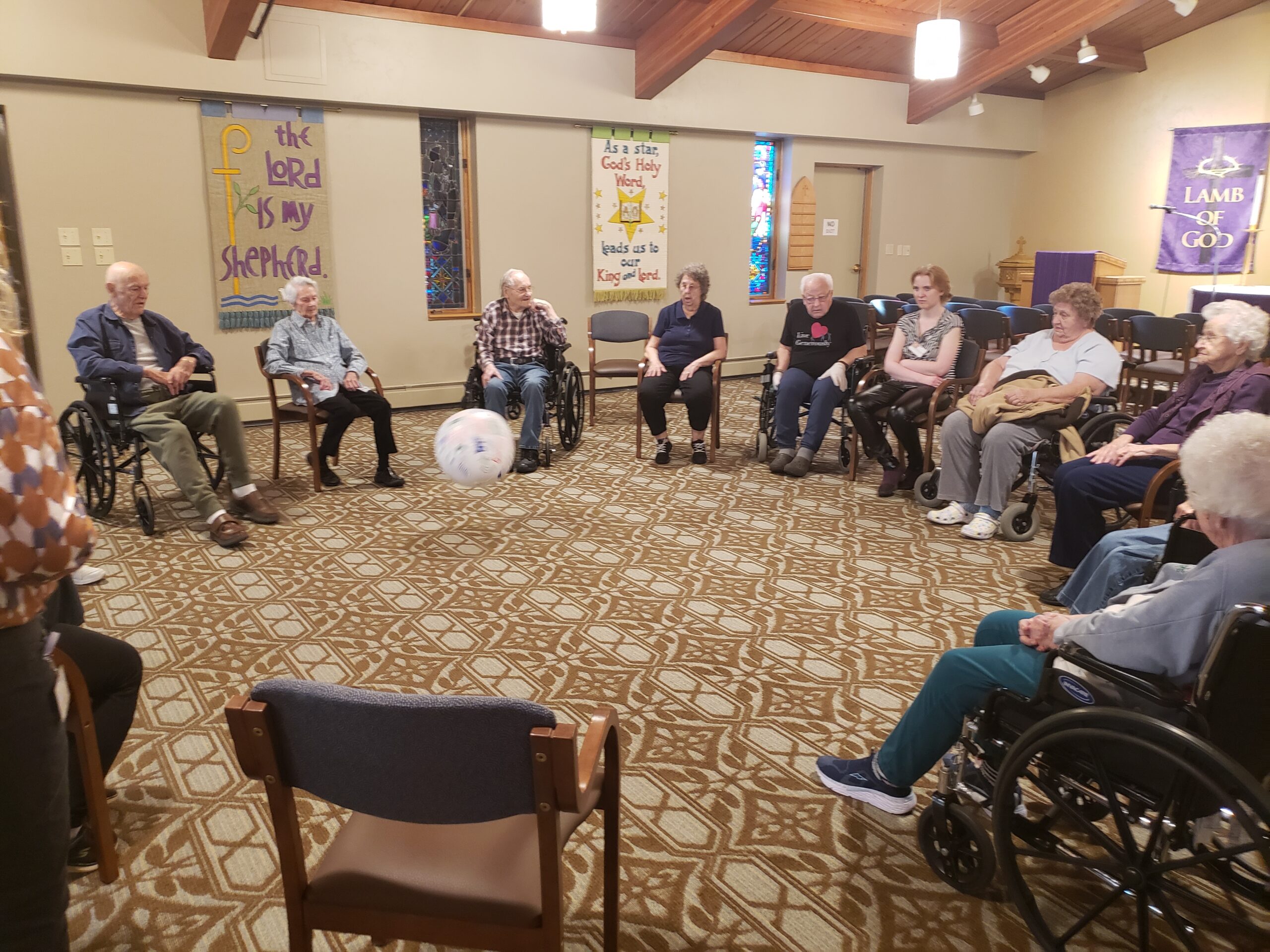 A diverse group of individuals in wheelchairs gathered together in a well-lit room, engaged in conversation and interaction.